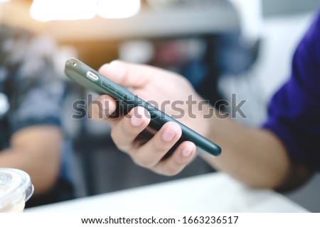 A man holding a smart phone, side view at cafe.