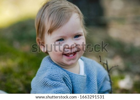 first teeth. portrait of a little two year old girl. baby laughs sincerely. little emotional baby. blue-eyed baby. little girl in a grey sweater. a gentle family photo. natural beauty. 