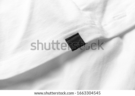 Closeup shirt clothing tag, label blank mockup template, to place your design on a white fabric background Royalty-Free Stock Photo #1663304545