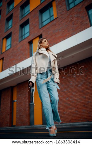Fashion style. Portrait in full growth, young beautiful blonde woman in jeans walking on the street, spring outdoors