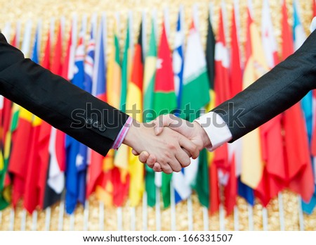 Businessmen shaking hands in front of the multi - national flag.    international business Royalty-Free Stock Photo #166331507
