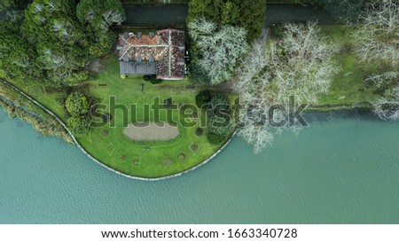 Aerial droe top view of a single farm house in a rural area beside a lake in Sao Miguel, Azores