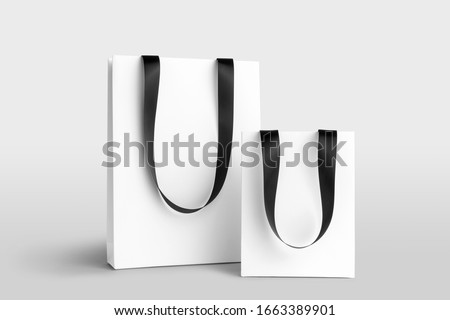 Composition of blank shopping bags mockup with ribbon hangers to place your design. Front view on white background. Fashion branding scene.