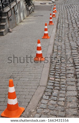 Traffic cone stay on paving stone street. Limit for parking.