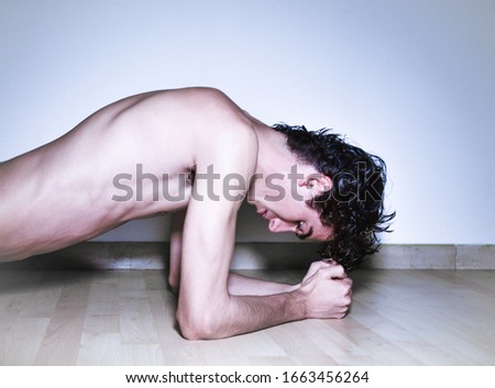 mediterranean Italian dark haired handsome male model boy with angel face and fit sportive shaped body exercising in Plank position on wooden floor and white background