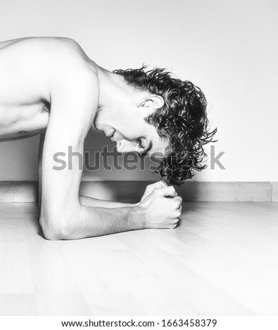 black and white photography.mediterranean Italian dark haired handsome male model boy with angel face and fit sportive shaped body exercising in Plank position on wooden floor and white background