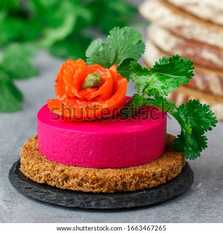 Beetroot and cream cheese (ricotta) mousse with salted salmon, fresh herbs and capers on slices of rye bread. A delicious holiday snack. Beet cheesecake. Selective focus, square picture