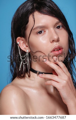 Portrait of beautiful Gothic woman with piercings and other accessories in studio on bue background. Emotional face. Human emotions, facial expression concept - thinking about problem, confused emotio