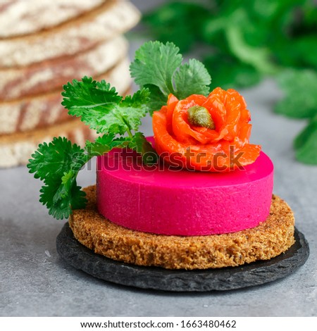 Beetroot and cream cheese (ricotta) mousse with salted salmon, fresh herbs and capers on slices of rye bread. A delicious holiday snack. Beet cheesecake. Selective focus, square picture