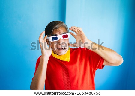 Old man in red t-shirt wearing 3D glasses, he get surprise that the things in the movie get through the display.