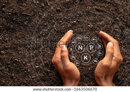 Men's hands are surrounded by rich soil with all the elements needed to grow, while digital icons represent the elements. Royalty-Free Stock Photo #1663506670