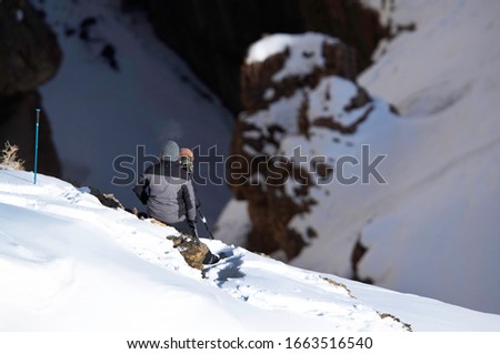 A photographer taking photo of Snow leopard near a deep gorge at Spiti Valley, India 