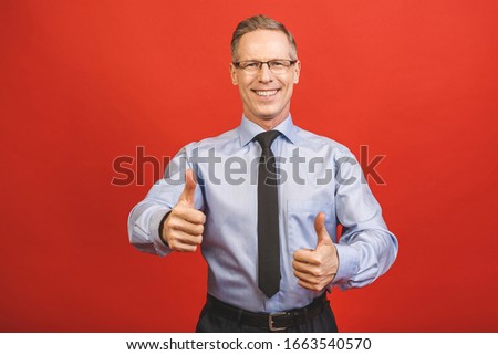 Well done! Close up portrait of delightful confident cool glad pleased cheerful excited aged senior business man demonstrating thumb up smile isolated on red background.