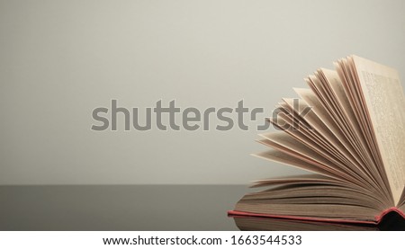 Beautiful open book on a gray and glass table background. 
