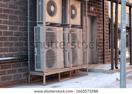 Air conditioners behind bars on the street. Near the door.