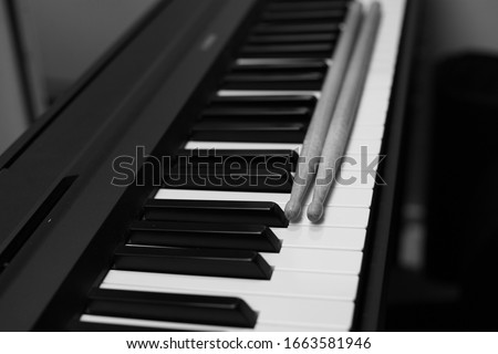 Piano and drumsticks. Black and white photo.
