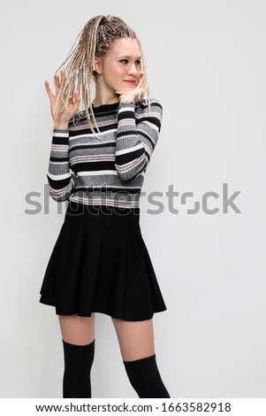 Beautiful blonde teenage girl with braids posing in studio. Style, trends, fashion concept.