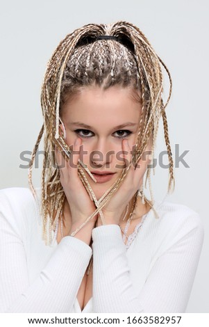 Beautiful blonde teenage girl with braids posing in studio. Style, trends, fashion concept.