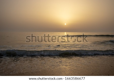 Beautiful sunset with sea waves breaking on the sand, at Mira beach in Aveiro, Portugal