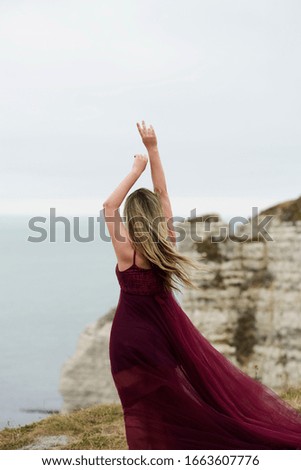 
etretat beach girl blonde stands back in dress coat normandy france cliffs nature park travel tourist
