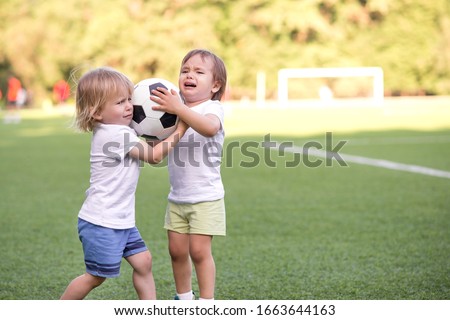 Two little toddlers arguing at football field or playground over soccer ball trying to take or grab ball. Conflict management, corporate fight metaphor and conflict resolving concept. Copy space Royalty-Free Stock Photo #1663644163