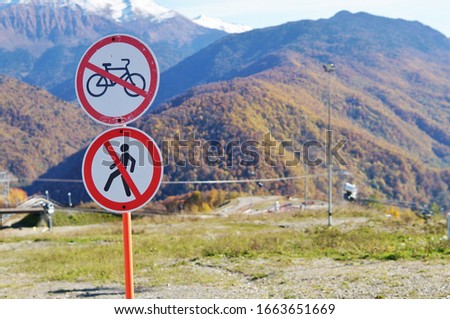 The signs "no entry" and "no bicycle allowed" are red circles with crossed out images of a bicycle and a pedestrian against the backdrop of the high Caucasus mountains.