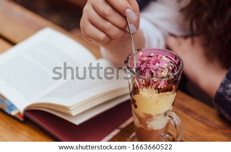
female hands, books and multi-colored ice cream with nuts