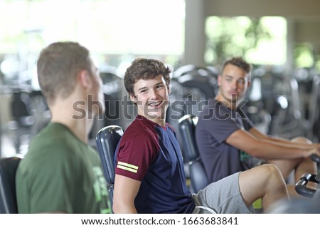 Teenage boys training on exercise bikes in gym Royalty-Free Stock Photo #1663683841