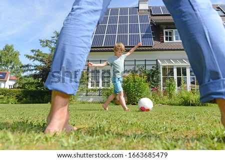 Father and son playing football in garden of solar paneled house Royalty-Free Stock Photo #1663685479