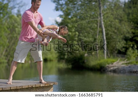 Man and young girl playing on jetty