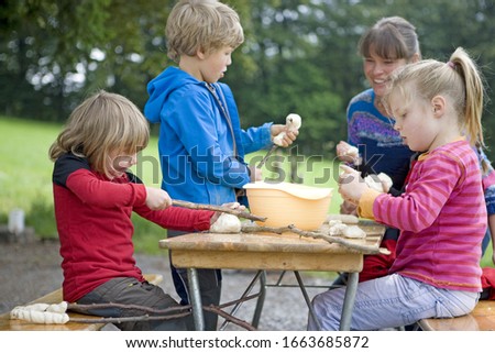 Kindergarten kids preparing campfire bread in a wood kindergarten
