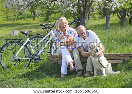Couple sitting with pet dog in meadow
