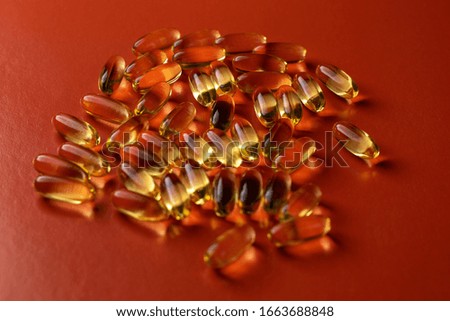 fish oil capsules on red background close-up