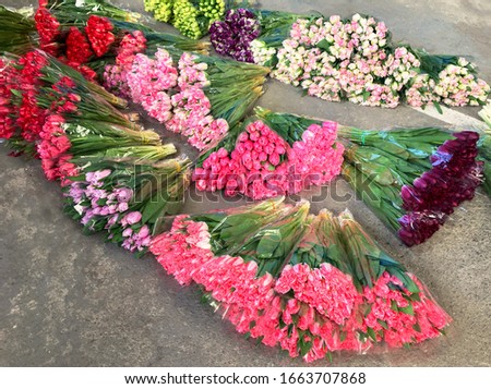 Many bouquets of bright, fresh tulips lie right on the pavement, a large assortment of flowers spread out on the floor, selective focus, top view