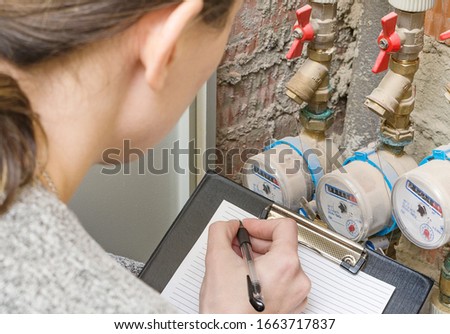 Householder checking the readout on a water meter. Payment of utility services, more expensive utilities, savings. Concept image. Royalty-Free Stock Photo #1663717837