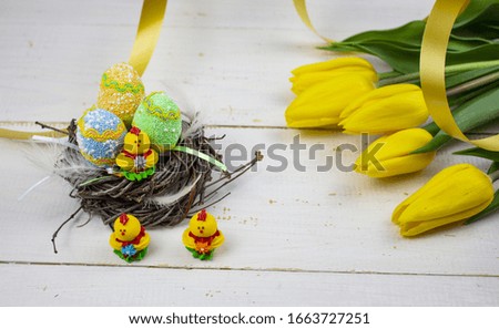 Easter eggs. Happy easter. Multi-colored Easter eggs. Easter eggs on a white wooden background. Yellow tulips. Tape. Place for text. Copy space