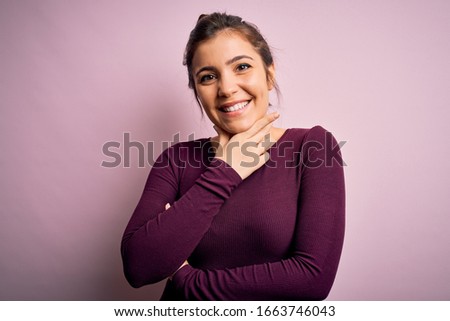 Beautiful young woman wearing casual bun hairstyle over pink isolated background looking confident at the camera smiling with crossed arms and hand raised on chin. Thinking positive.