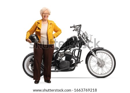 Full length portrait of a mature woman holding a helmet and standing next to a custom chopper motorcycle isolated on white background