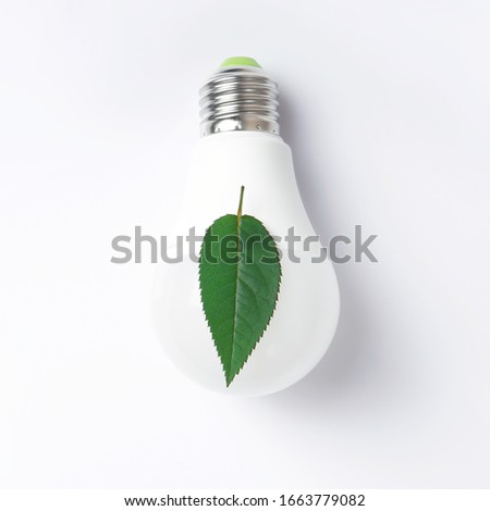 Green energy concept with a light bulb with green leaf on a white background. Cropped.