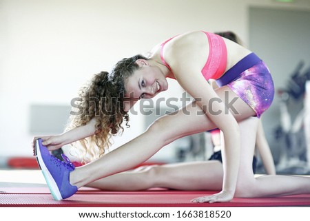 Portrait of teenage girl touching toes in gym