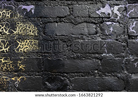 Black yellow purple gold painted brick wall with chip cracks