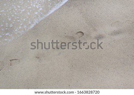 Shoe print of alone human way walk on sand beach with sea wave 