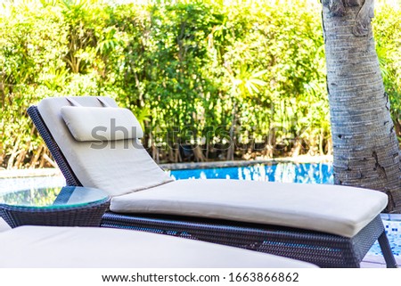 Empty chair deck lounge around swimming pool in hotel resort for travel vacation
