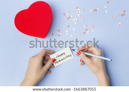 Top view of female writing a note for Mother's day on a blue background