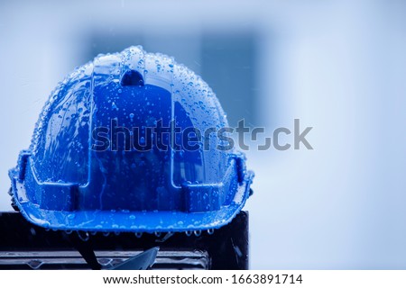 Raindrops on a construction helmet,heavy rain and construction safety helmets, blue hard safety helmet and raining  Royalty-Free Stock Photo #1663891714