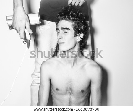 black white photography, portrait of expressive mediterranean Italian dark haired handsome male boy model angel face and fit sportive body posing for casual shooting with hair blower and hair dresser