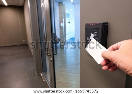 Men hand reaching to use RFID key card to access to office building area and workspace. In building security only for authorized person