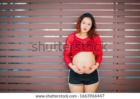 Pregnant women use both hands to hold their stomach happily.