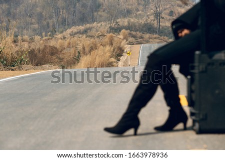 Girl in black walking alone on mountain highway 