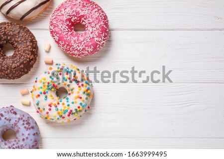 Yummy donuts and space for text on white wooden background, flat lay